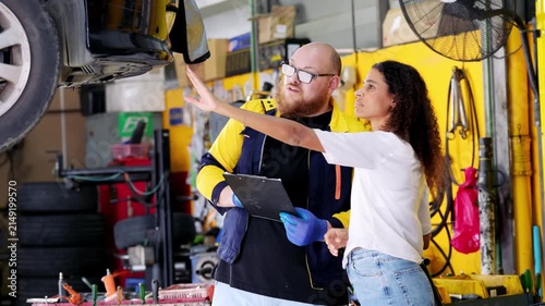 Professional mechanic and customer discussing vehicle repair in garage collaborative automobile maintenance expert explaining car to client
