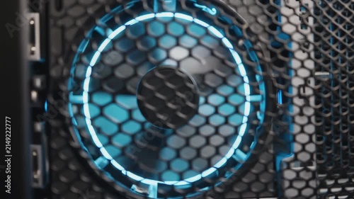 Close-up of a computer cooling fan with blue LED lighting behind a hexagonal mesh grill.