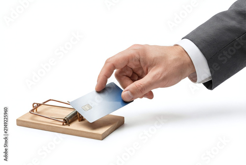 Hand placing credit card onto wooden mousetrap