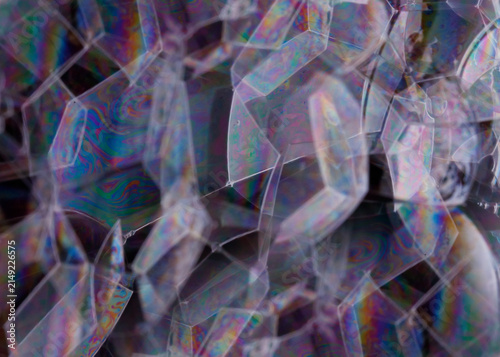 Close-up abstract showing geometric soap-film facets and layered thin-film color patterns.