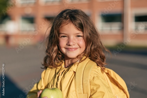 Happy young girl with backpack and apple ready for school