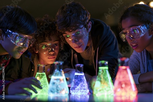 Children in safety goggles observe glowing liquids in laboratory flasks during an experiment