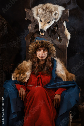 Fotografie Woman in Blue and Red Medieval Slavic Style Sitting on Throne