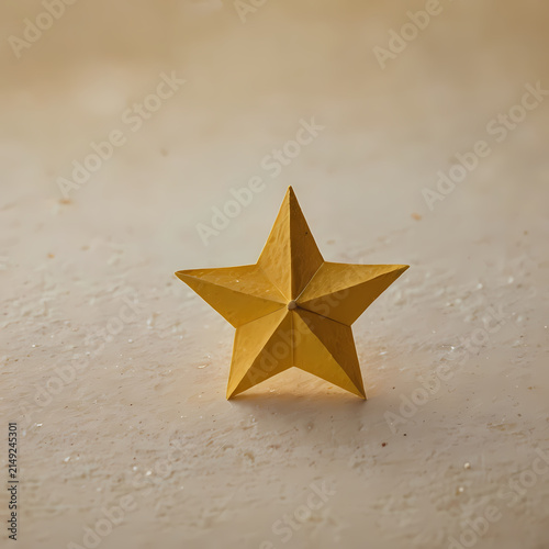 Golden geometric folded paper star on warm textured handmade paper with minimalist Christmas styling