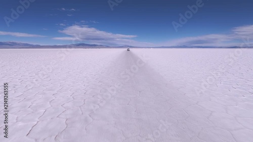 Driving across Salinas Grandes salt flats in Jujuy Argentina. Drone high view, car front POV
