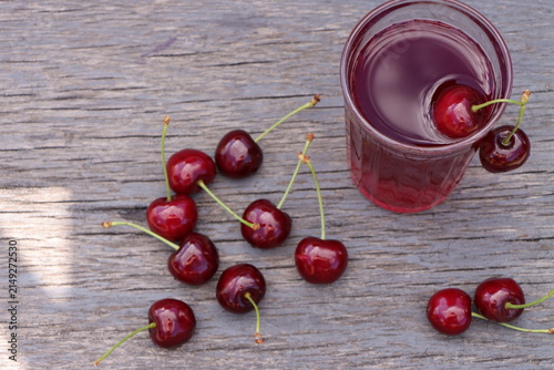Fotografie Composition with cherry drink in a glass and fresh berries on retro wood