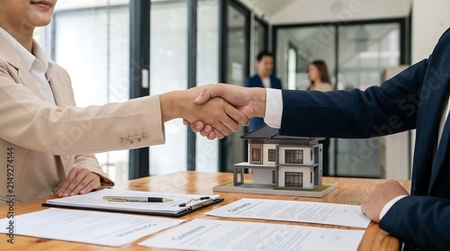 Professional business partners handshake for real estate property deal agreement with house model and contract documents