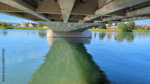 Sunlight reflections dancing on the concrete bottom surface of a bridge over water