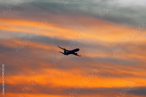 Dark silhouette of an airplane flying in the sunset sky