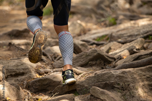 Legs runner in compression sleeves running over stones
