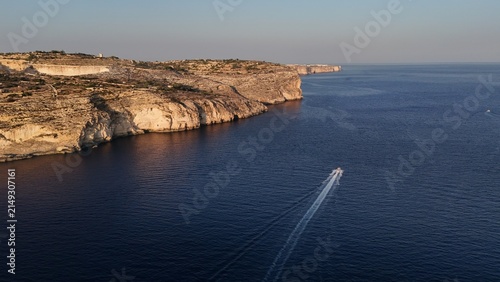 Canvas Print Beautiful aerial photography of a shi passing by the coast, near the blue grotto, Malta, during a lovely summer sunset overt the island