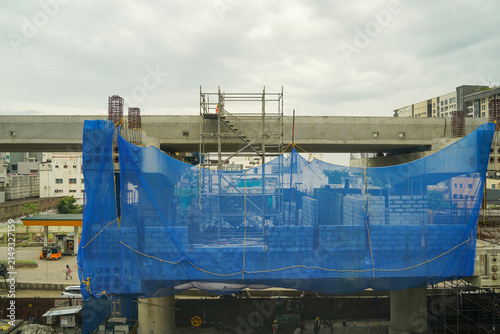 Obraz na płótnie Metro rail bridge construction wrapped in blue safety netting over the city