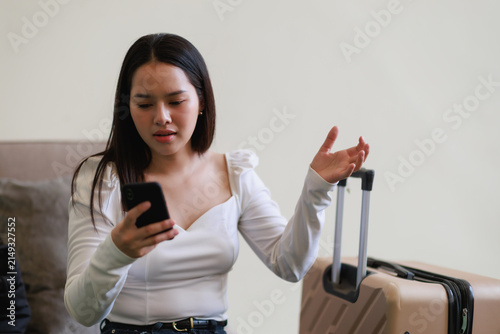Принти на полотні Young Asian woman feeling frustrated and confused while checking her smartphone