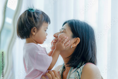 Little daughter gently touching her mother face, expressing love, trust, family bonding, warmth, care, happiness, and precious moments together at home, Asian Thai people