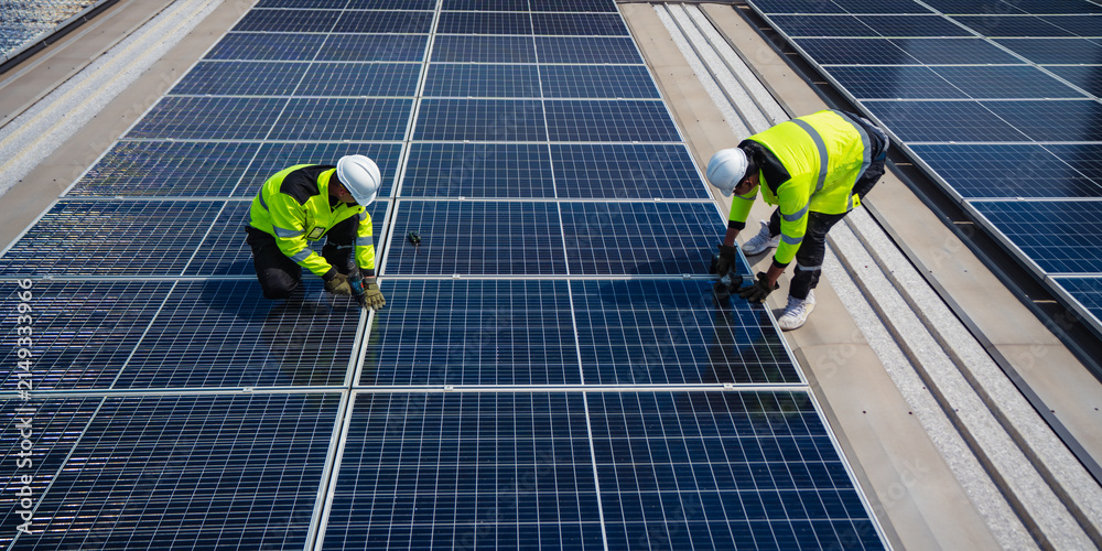 Obraz premium Solar electricity power technology for sustainable energy, solar panel worker rooftop installation safety vest hard hat renewable energy maintenance technician electricity solar panel worker