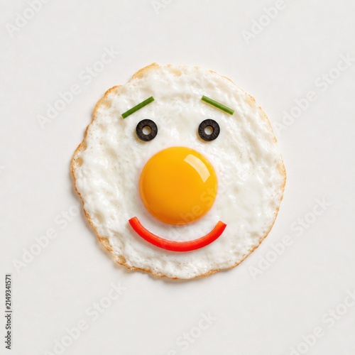Happy fried egg face made with vegetables on white background