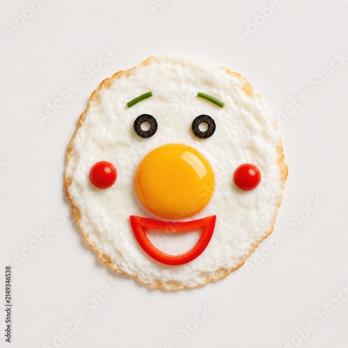 Happy smiling fried egg face made with vegetables on white background