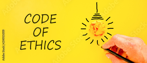 Code of ethics words symbol. Concept words Code of ethics on beautiful yellow paper. Beautiful yellow background. Light bulb icon. Businessman hand. Business Code of ethics concept. Copy space.
