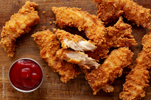 Organic Crispy Chicken Strips with Ketchup on a Wooden Board, top view. Close-up.