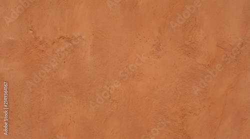 Terracotta textured plaster wall background for design projects. Rustic orange stucco surface with natural imperfections and warm earthy tones.