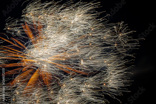 Golden fireworks display with intricate sparkling light trails and orange rays