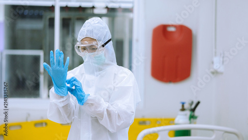 Quadro su tela Healthcare Worker Adjusting Blue Rubber Gloves Wearing Full PPE Suit and Goggles