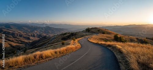 Winding mountain road through scenic golden hills at sunset