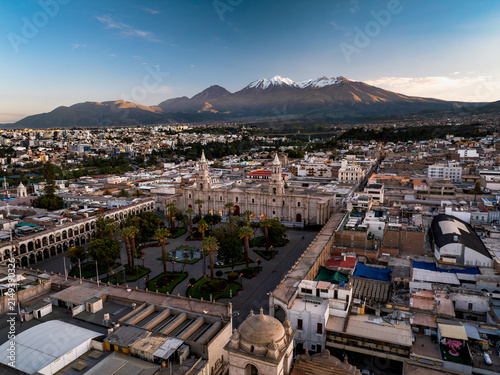 Aerial view of Plaza de Armas Arequipa with its historic cathedral, colonial buildings, palm trees, and the snow-capped Misti volcano in the background in Arequipa, Arequipa, Peru.