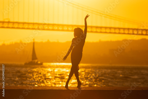 Dancer performs at sunset by the bridge with boat in the background