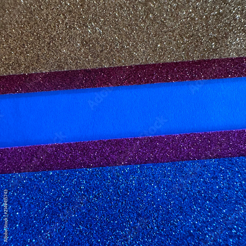 Horizontal layers of gold, purple, and blue glitter paper textures