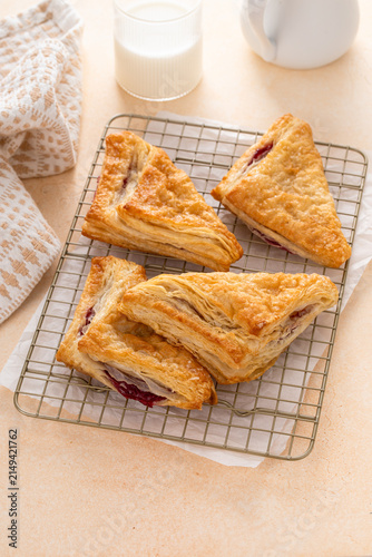 Puff pastries turnovers with cherry or berry jam on a baking sheet freshly baked and ready to eat