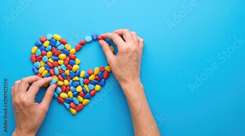 Hands arranging colorful small beads into a heart shape to celebrate teachers day with love and appreciation
