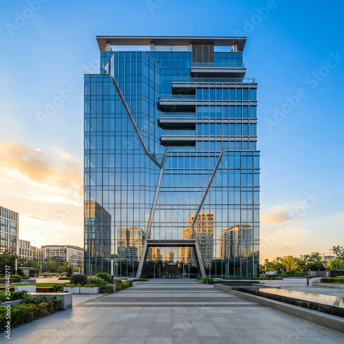 Modern glass skyscraper in urban plaza at sunset