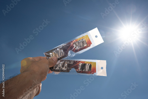Hand Holding Solar Eclipse Glasses Against the Sun