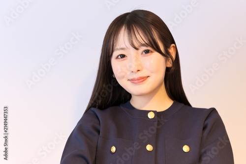 優しく穏やかな笑顔を向けるオフィスカジュアル姿の若い女性のポートレート