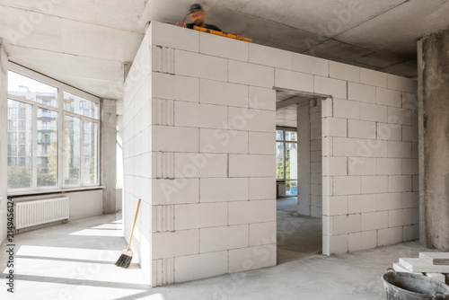 Trabajo en construcción de una pared en un espacio interior con ventanas grandes que dan luz natural al área
