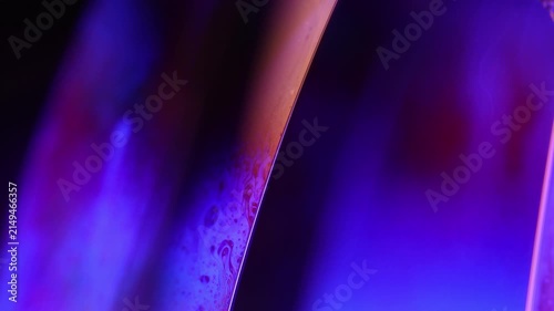 Glowing violet and amber liquid film boundary with subtle marbling. Deep violet and blue backlighting illuminates a vertical fluid plane boundary.