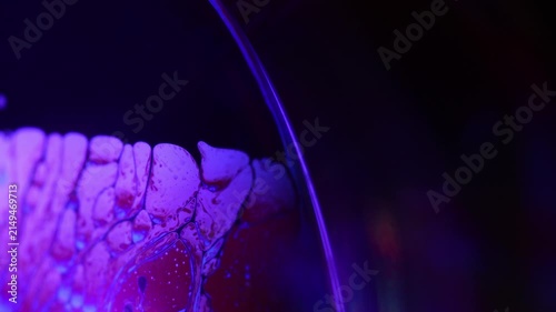 Glowing violet fluid film with intricate cellular marbling. Vibrant violet and magenta backlighting illuminates a horizontal liquid plane boundary.
