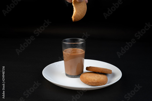 Traditional Indian tea in a clear glass and Biscuit isolated on a black background