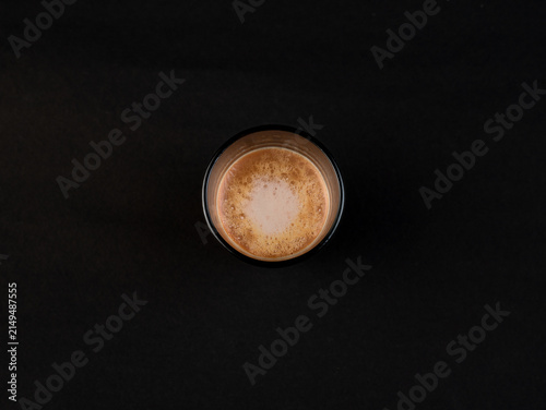 Traditional Indian frothy tea in a clear glass isolated on a black background