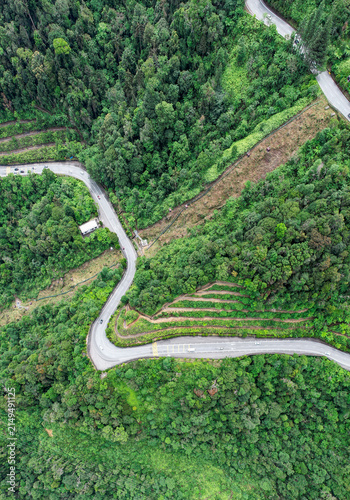 Aerial view of a winding mountain road cutting through the dense tropical forest of Genting Highlands, Pahang, Malaysia.