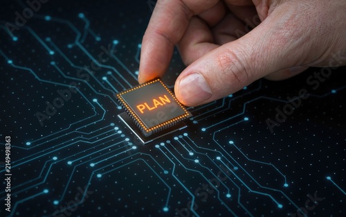 Hand placing a microchip with the word plan onto a digital circuit board