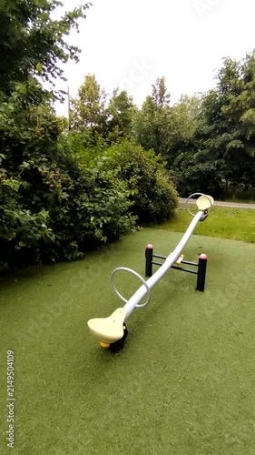Playground seesaw positioned on artificial grass in a lush park  