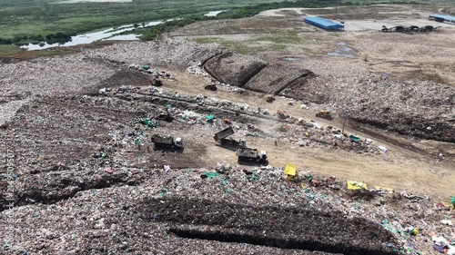 Garbage trucks dumping waste along the edge of an active landfill