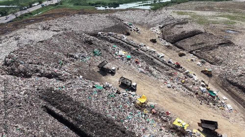 Waste trucks unloading garbage at a sprawling open landfill