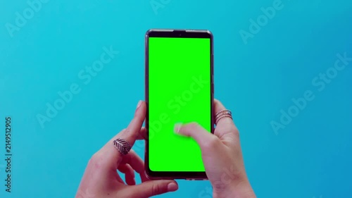 Hands Holding Smartphone with Green Screen on Blue Background