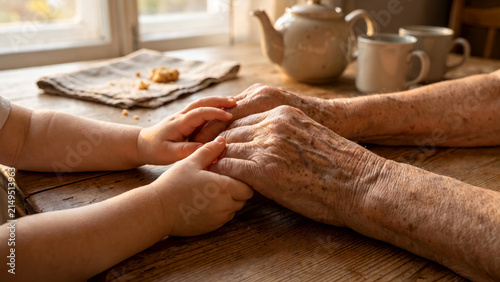 Childs small hands gently hold elderly grandmothers hands. Heartfelt moment of care, family love, emotional support and meaningful connection between generations. Care, caregiving, aging, family