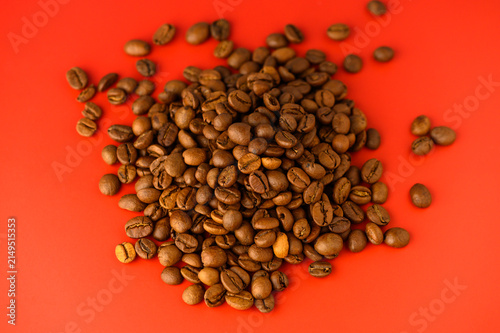 Konstfotografi An array of roasted coffee beans lies on a bright red background, showcasing their rich brown hues and shiny surfaces