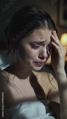 Young woman crying and touching forehead in bedroom at night close up shot