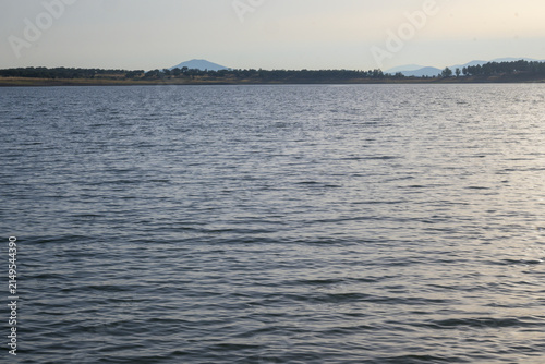 Obraz na plátně Calm lake with distant mountains at sunset